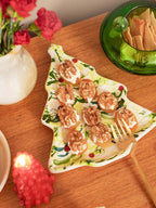 Prato de servir em formato de pinheiro de Natal, feito de cerâmica artesanal branca com pintura verde e delicados detalhes vermelhos. A peça possui tamanho de 15 x 23 cm, com design autoral Lolahome produzido no Brasil, apresentando as variações charmosas de uma peça feita à mão, ideal para uma mesa posta exclusiva e inspiradora.