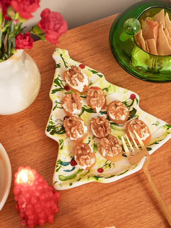 Prato de servir em formato de pinheiro de Natal, feito de cerâmica artesanal branca com pintura verde e delicados detalhes vermelhos. A peça possui tamanho de 15 x 23 cm, com design autoral Lolahome produzido no Brasil, apresentando as variações charmosas de uma peça feita à mão, ideal para uma mesa posta exclusiva e inspiradora.