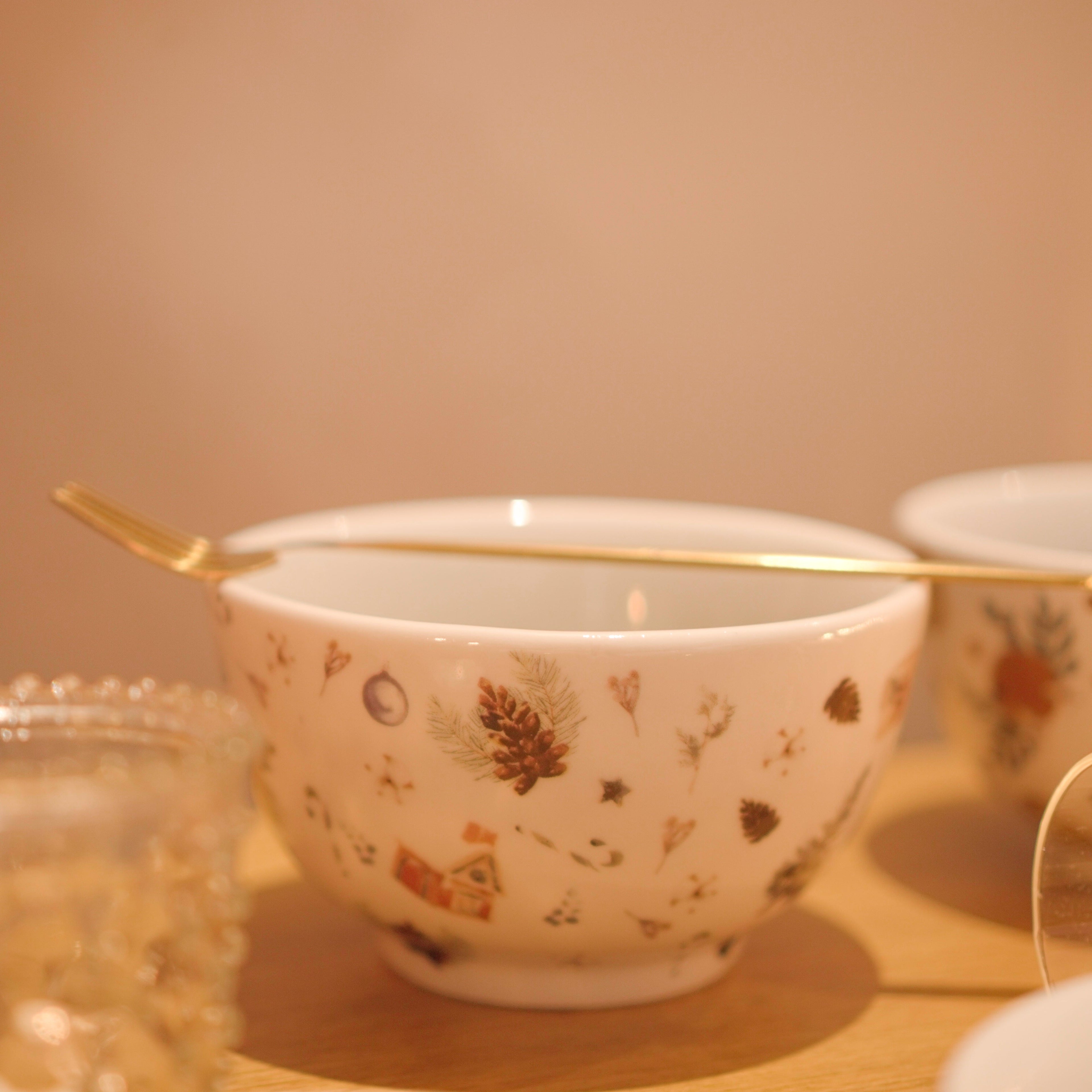 Bowl redondo de porcelana branca da coleção Pinha, decorado com uma estampa festiva de pinhas, folhagens e elementos natalinos em tons de verde, marrom e vermelho. A peça possui tamanho de 14 cm de largura e 7 cm de altura, com design autoral Lolahome desenvolvido no Brasil, apresentando um acabamento refinado e temático. Como deve ser usado: ideal para compor uma mesa posta natalina chic e acolhedora, sendo perfeito para servir petiscos, sobremesas, caldos ou pequenas porções com o charme das festas