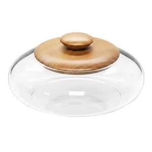 Redoma de vidro transparente em formato cilíndrico com topo arredondado, posicionada sobre uma base circular de madeira clara com acabamento natural.