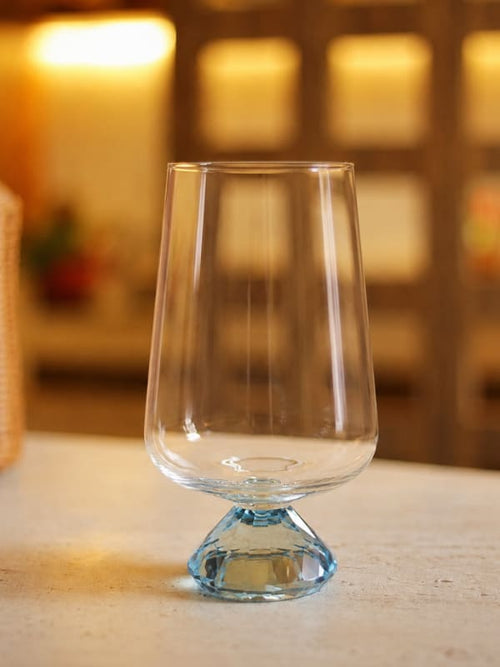 Copo de vidro Diamond azul 290ml sobre mesa clara com ambiente decorado ao fundo
