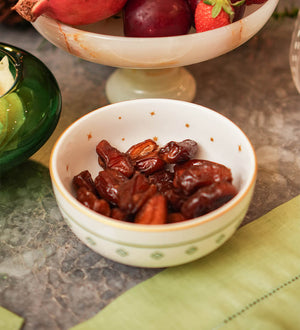 Bowl redondo de porcelana branca da coleção Zahidi, apresentando estampa exclusiva com detalhes em verde e dourado. A peça possui tamanho de 12 cm de diâmetro por 8 cm de altura, com design autoral Lolahome produzido no Brasil, garantindo um acabamento chic e atemporal para a mesa posta.