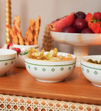 Bowl redondo de porcelana branca da coleção Zahidi, apresentando estampa exclusiva com detalhes em verde e dourado. A peça possui tamanho de 12 cm de diâmetro por 8 cm de altura, com design autoral Lolahome produzido no Brasil, garantindo um acabamento chic e atemporal para a mesa posta.