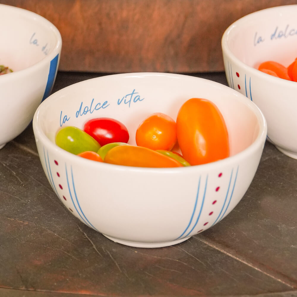 Bowl redondo de cerâmica artesanal branca da coleção La Dolce Vita, apresentando estampa exclusiva com detalhes em tons de marsala e azul. A peça possui tamanho de 13 cm, com acabamento manual e design autoral Lolahome, destacando as variações únicas de cor e forma de um produto produzido de forma artística no Brasil.