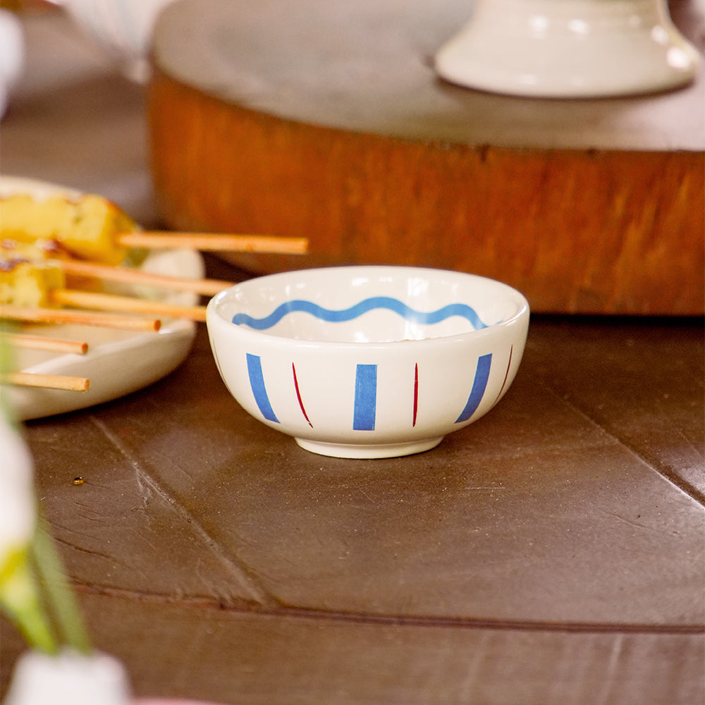 Molheira redonda de cerâmica artesanal branca da coleção La Dolce Vita, com delicados detalhes pintados à mão nas cores marsala e azul. A peça possui design autoral Lolahome com tamanho de 10 cm, apresentando acabamento rústico e sofisticado com as variações únicas de um produto feito à mão.