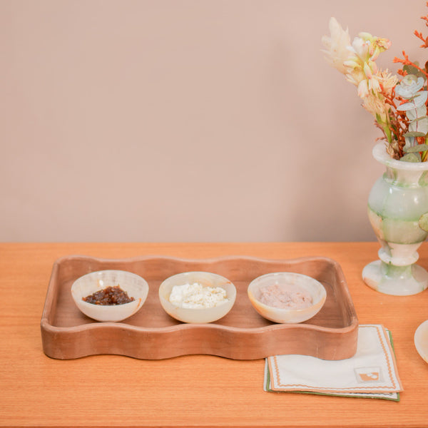 Bowl redondo pequeno de pedra natural ônix na cor marfim, com acabamento polido e brilho suave. A peça possui tamanho de 10 cm de largura e 4 cm de altura, apresentando design atemporal e variações únicas de veios e tonalidades naturais, características de um produto exclusivo. Como deve ser usado: ideal para compor a decoração ou mesa posta chic, sendo perfeito para servir petiscos, pequenas porções de castanhas ou para organizar acessórios com muita personalidade.